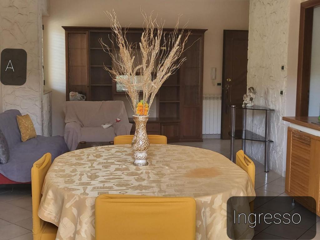 einem Esstisch mit gelben Stühlen und einer Vase darauf in der Unterkunft La Pace Case vacanza in Campora San Giovanni