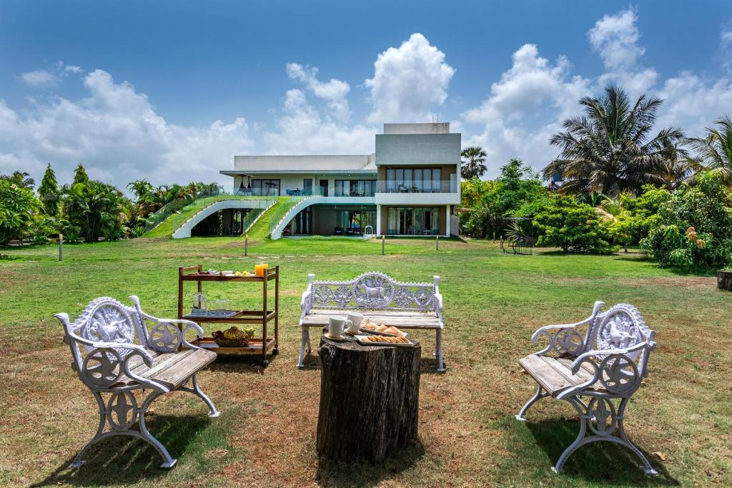 a house with three chairs and a tree stump at SaffronStays Gardenia, Alibaug in Kīhīm