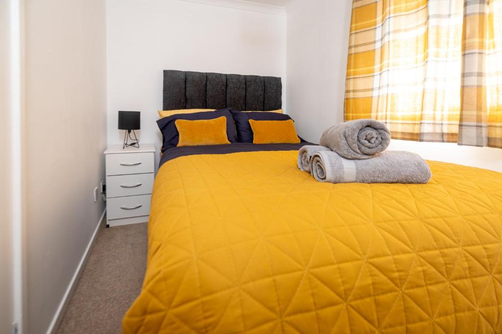 a bedroom with a yellow bed with towels on it at Beautiful Abode, Fast Wifi, Parking, Frenchay in Bristol