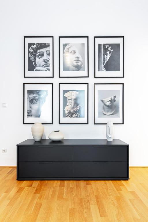 a living room with a black dresser and framed pictures at Trendy apt with - smart TV, coffee machine in Meidling in Vienna