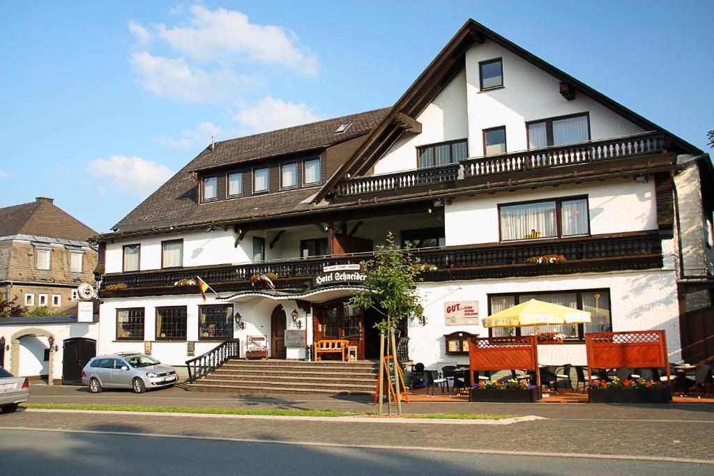 een gebouw waar een auto voor geparkeerd staat bij Hotel Schneider in Winterberg