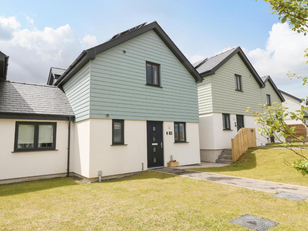 a home with a green and white house at 15 Parc Delfryn in Brynteg