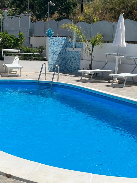 een groot blauw zwembad met stoelen en tafels bij Miriasol Bed and Breakfast in Capo Vaticano