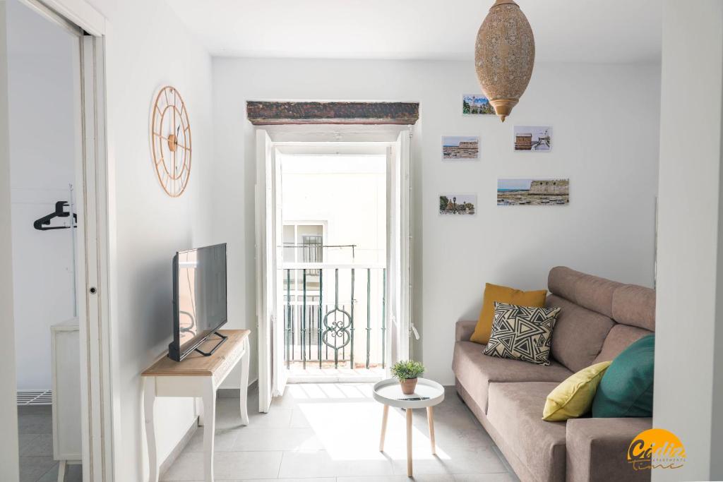 een woonkamer met een bank en een televisie bij Casa Rehala by Cadiz Time in Cádiz