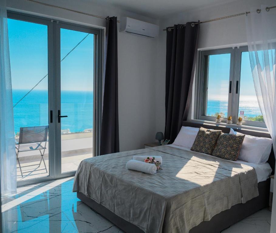 a bedroom with a bed with a view of the ocean at Ionian Pearl in Dhërmi