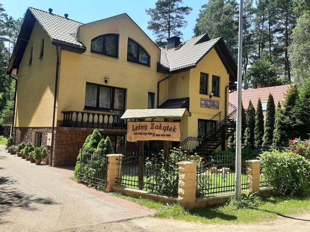 una gran casa amarilla con un cartel delante en Leśny Zakątek, en Krasnobród