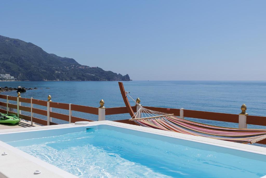 アギオス・ゴルディオスにあるVilla Renata & Villa Filippos with private Plunge Pool by Konnectのハンモック付きのスイミングプールと海