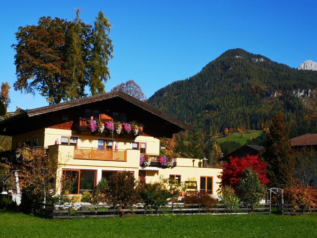 ein Haus mit Blumen auf dem Balkon in den Bergen in der Unterkunft Haus Alpengruß in Lofer