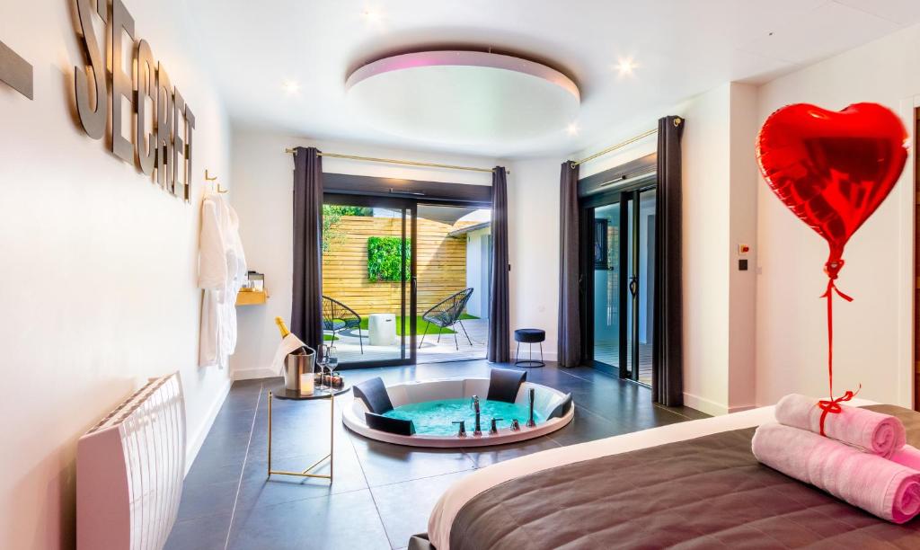 una camera con letto e vasca con cuore di Le Secret - Nuit romantique avec Jacuzzi privatif - Champagne offert - Climatisation a Nantes