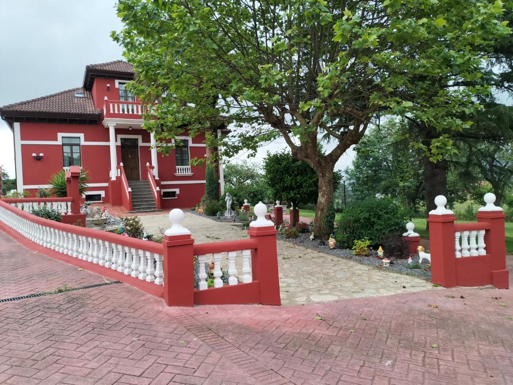 a red fence in front of a red house at Villa Burión in Llanera
