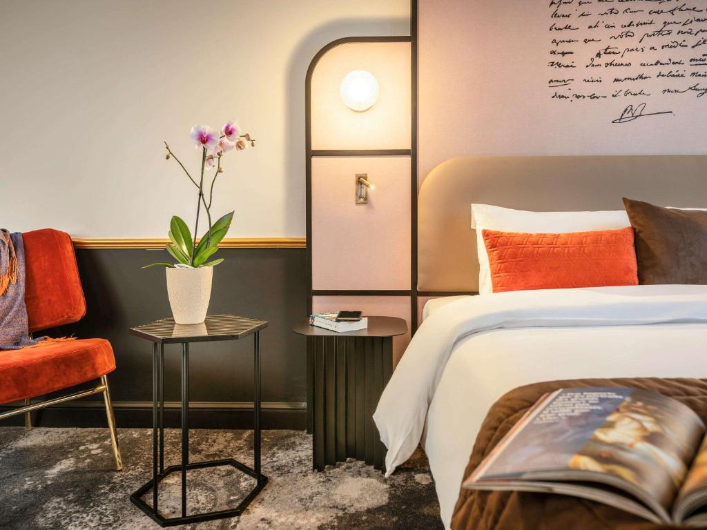 1 dormitorio con 1 cama y un jarrón con flores en Mercure Versailles Paris Ouest, en Le Chesnay