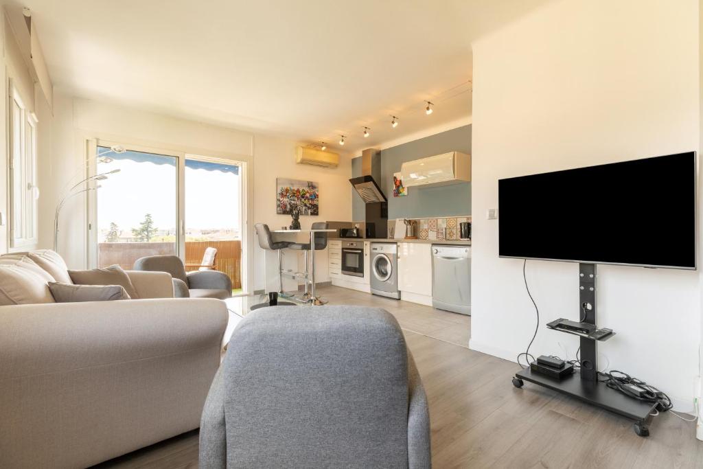 salon z telewizorem z płaskim ekranem na ścianie w obiekcie Hayda - Proche plage et congrès w Cannes