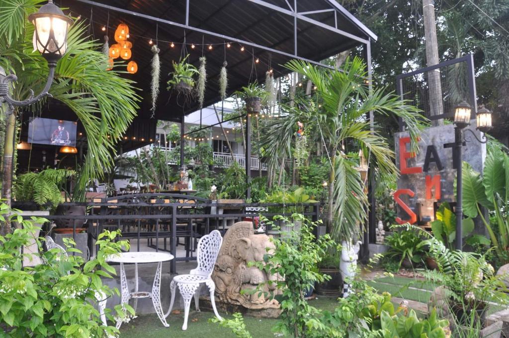 a garden with chairs and tables and plants at Eat n Sleep in Phuket Town