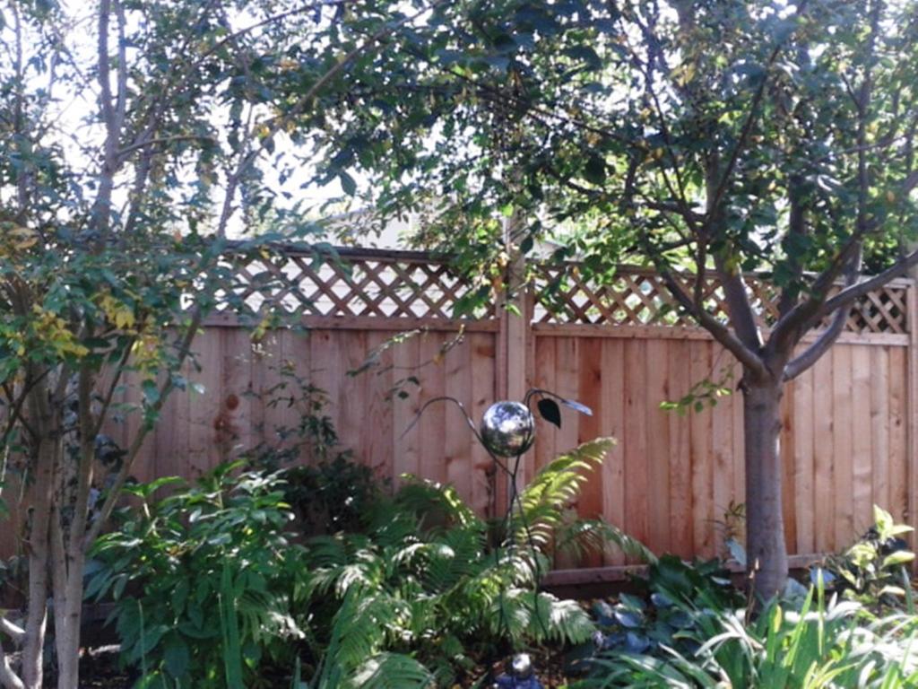 a wooden fence with a tree in front of it at Phoenix House B&B in Stettler