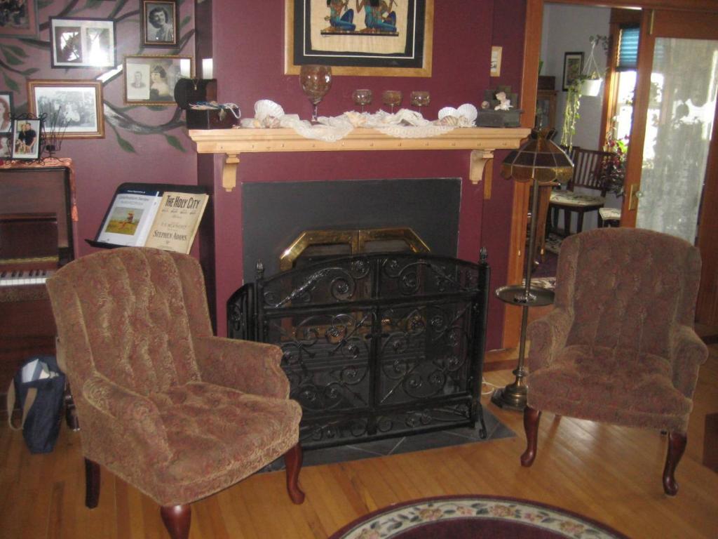 a living room with a fireplace and two chairs at Phoenix House B&B in Stettler