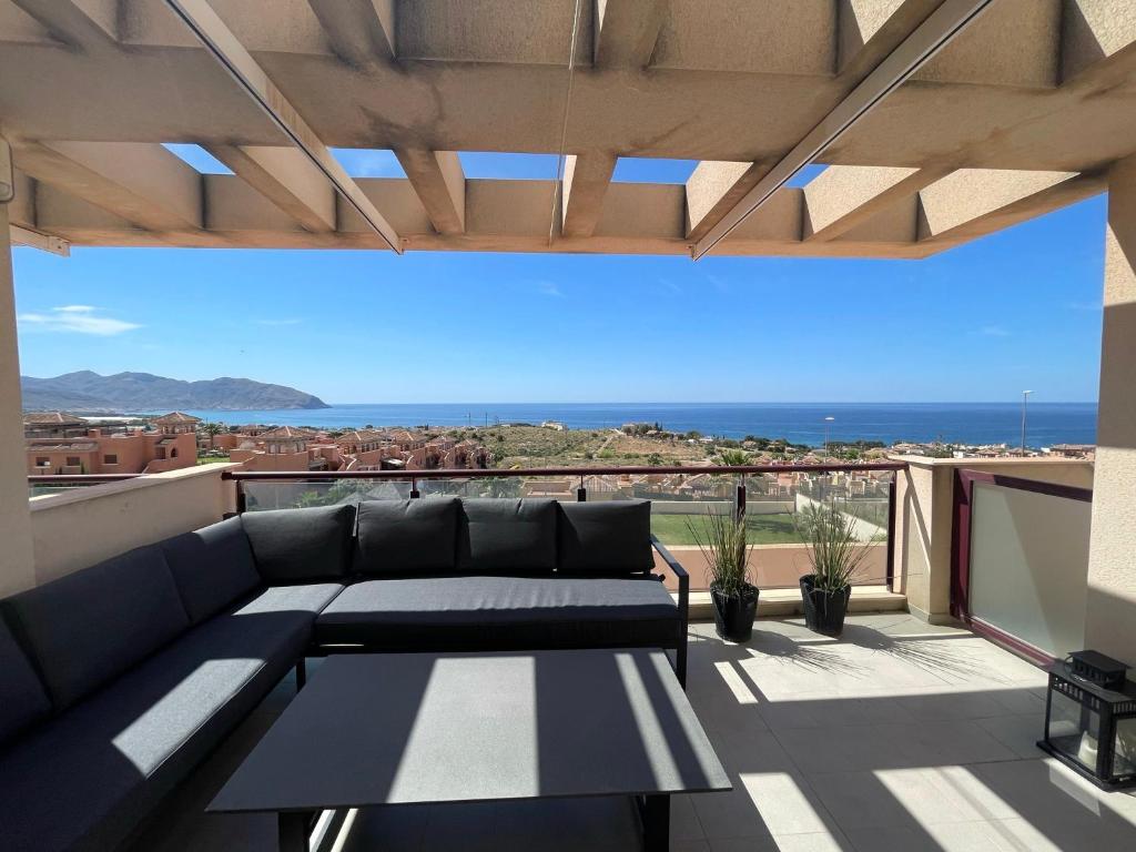 a patio with a couch and a view of the ocean at Sea view pool apartment Mojon hills in Isla Plana