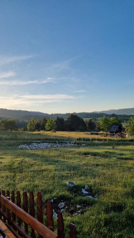 a wooden fence in a field with a creek at A Pine vikendica u srcu Zapadne Srbije in Nova Varoš