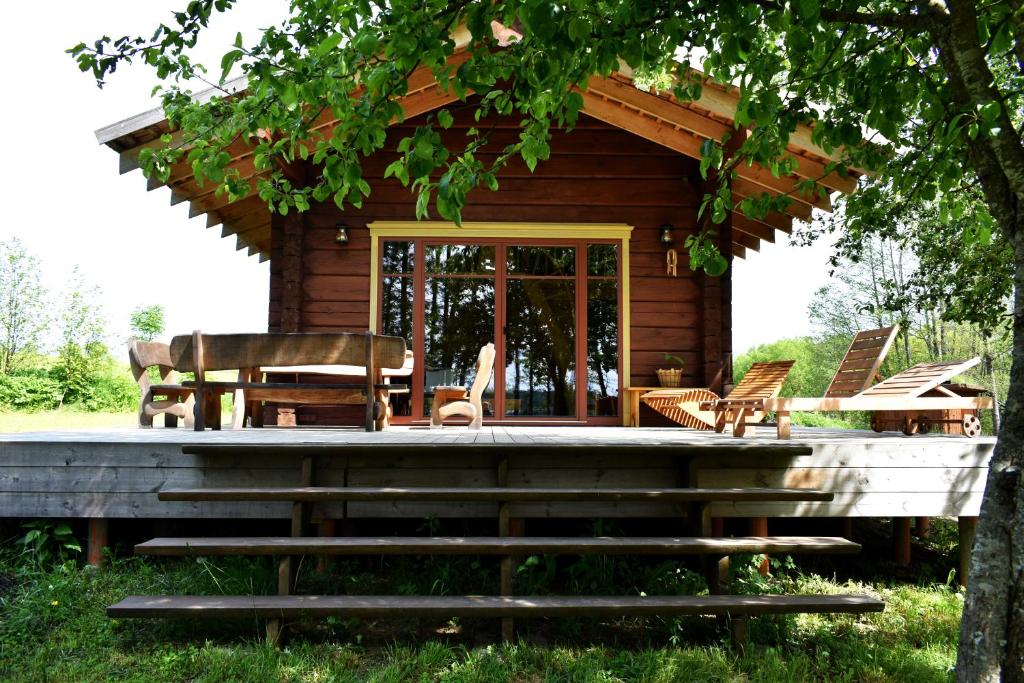 Cette cabane en rondins dispose d'une terrasse couverte, d'une table et de chaises. dans l'établissement Kaimukas - namelis prie ežero keturiems, à Dvarčėnai