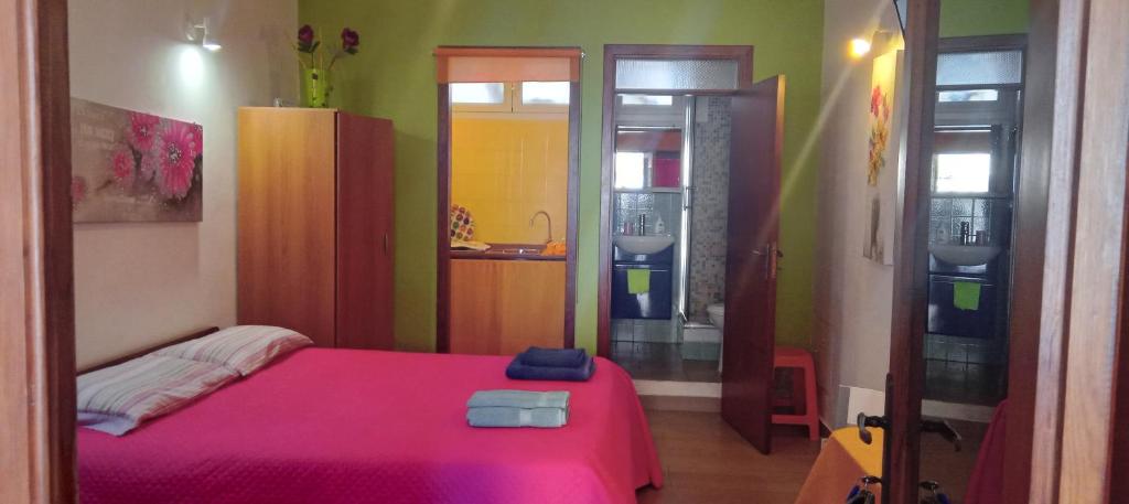 una camera con letto rosa e un bagno di Appartamento Seflonia a Cefalù