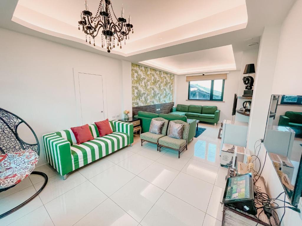 een woonkamer met groene en rode stoelen en een kroonluchter bij 宜蘭馬堡莊園10-28人包棟民宿 in Shangwu