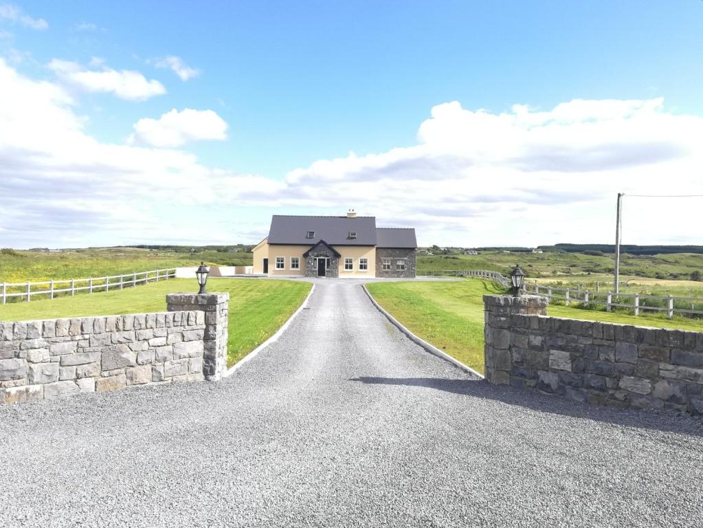 una carretera que conduce a una casa de campo con una pared de piedra en Glenmore House - ROOM ONLY en Doolin