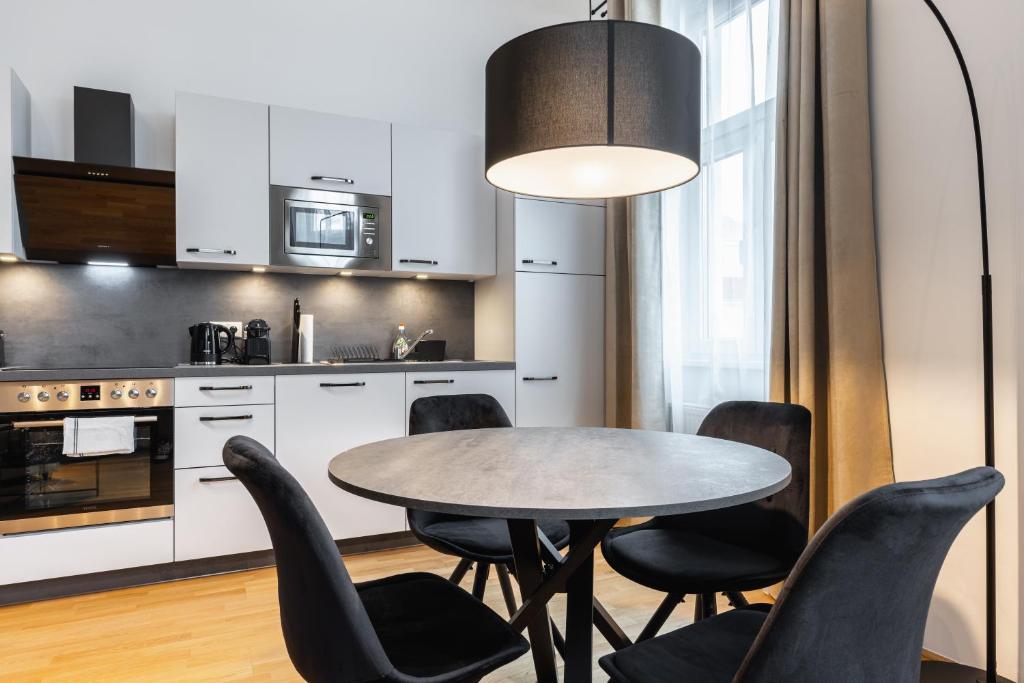 a kitchen with a table and black chairs at Trendy apt with - smart TV, coffee machine in Meidling in Vienna