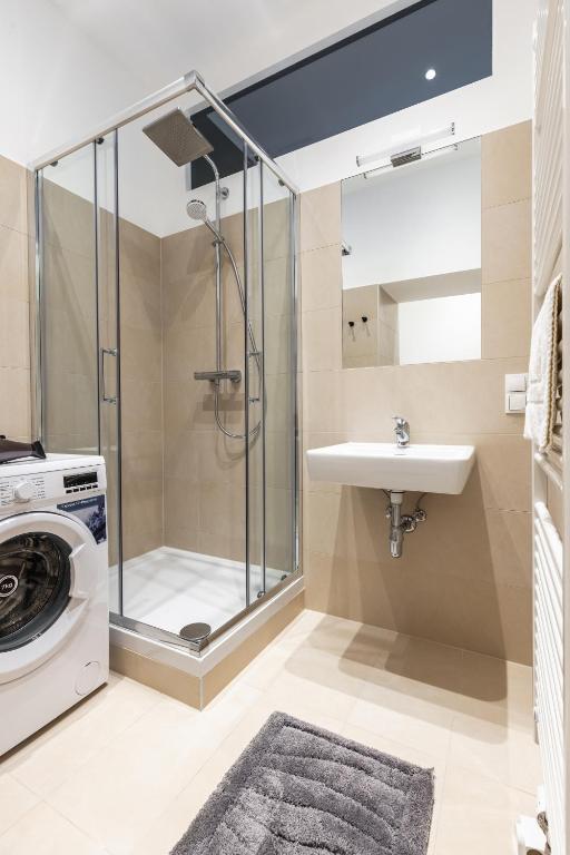 a bathroom with a shower and a sink and a washing machine at Trendy apt with - smart TV, coffee machine in Meidling in Vienna