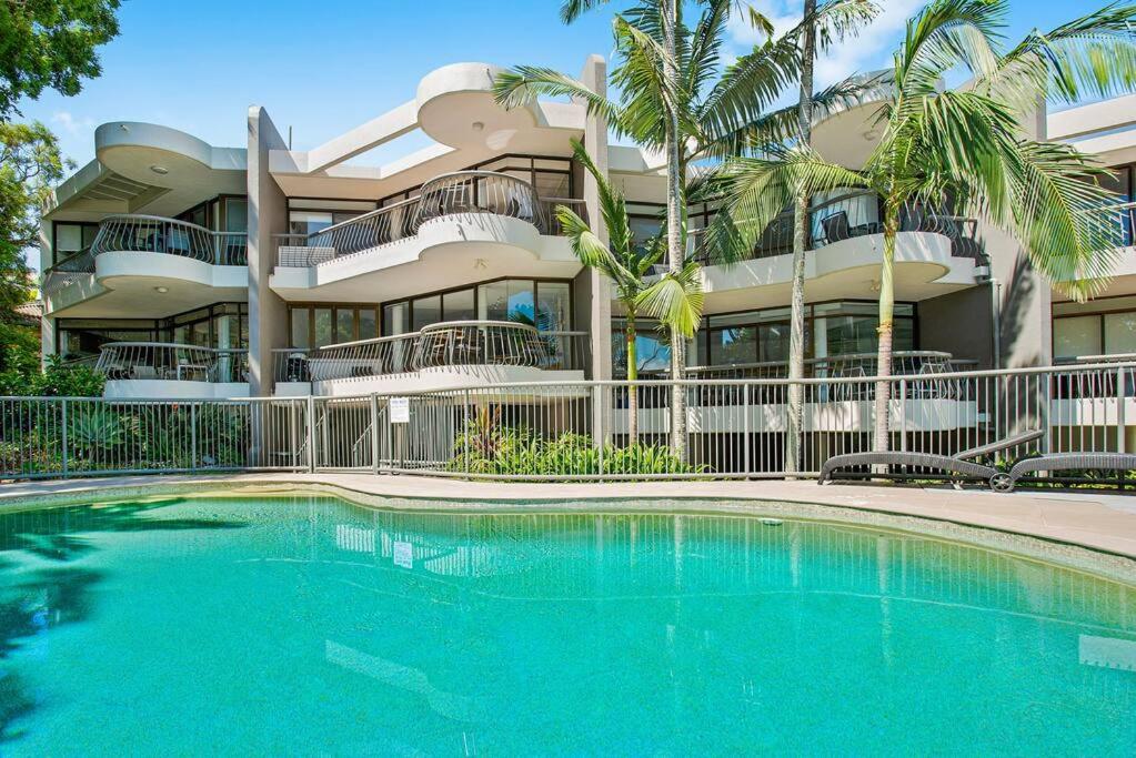 a building with a swimming pool in front of a building at Tranquil Noosa at its best Beach, Bush, Good Food. in Noosa Heads