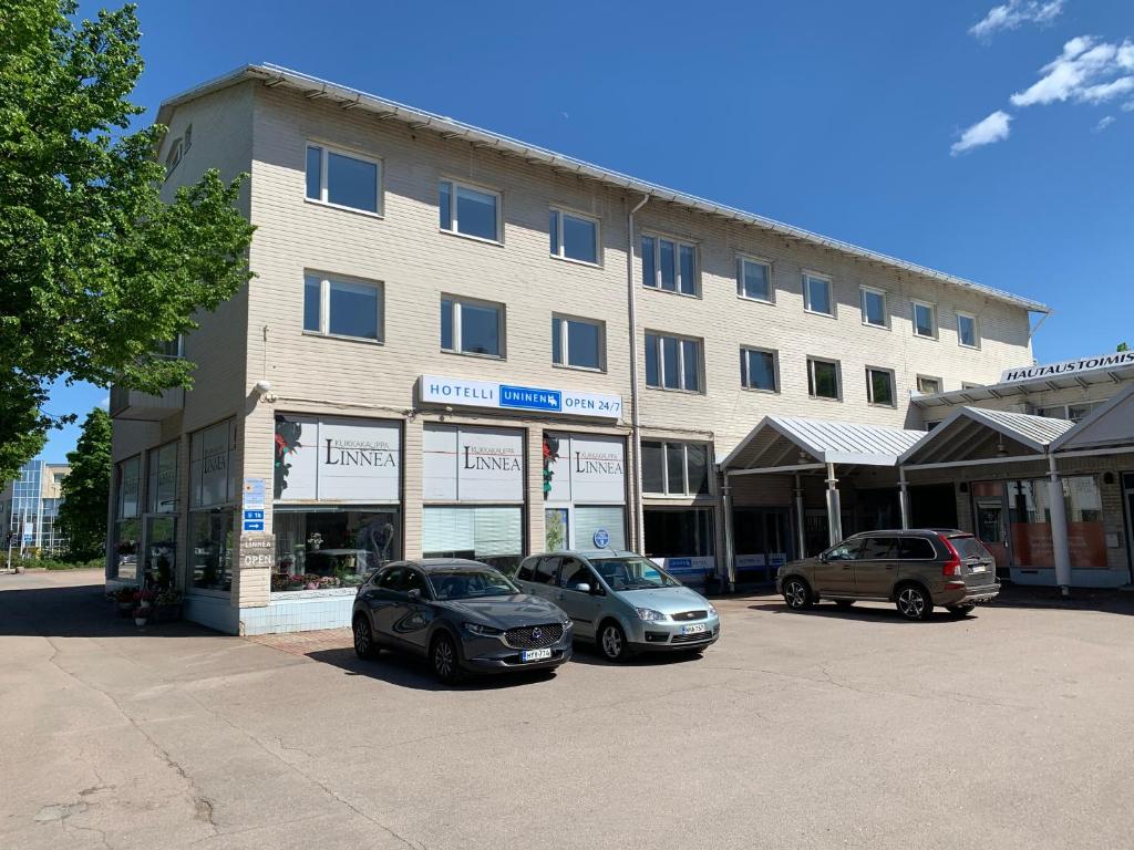 two cars parked in a parking lot in front of a building at Hotelli Uninen Kotka in Kotka