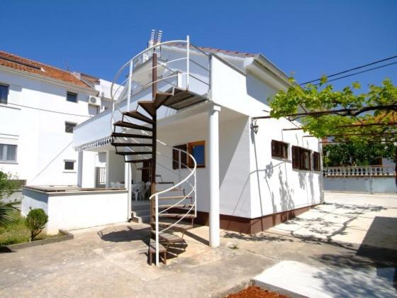 a white house with a spiral staircase in front of it at Diklo beach apartments 1 in Zadar