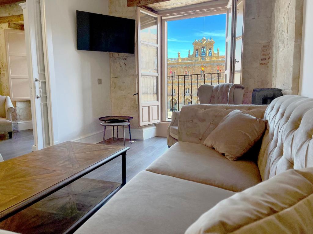 a living room with a couch and a large window at Apartamentos El Mirador del Poeta in Salamanca