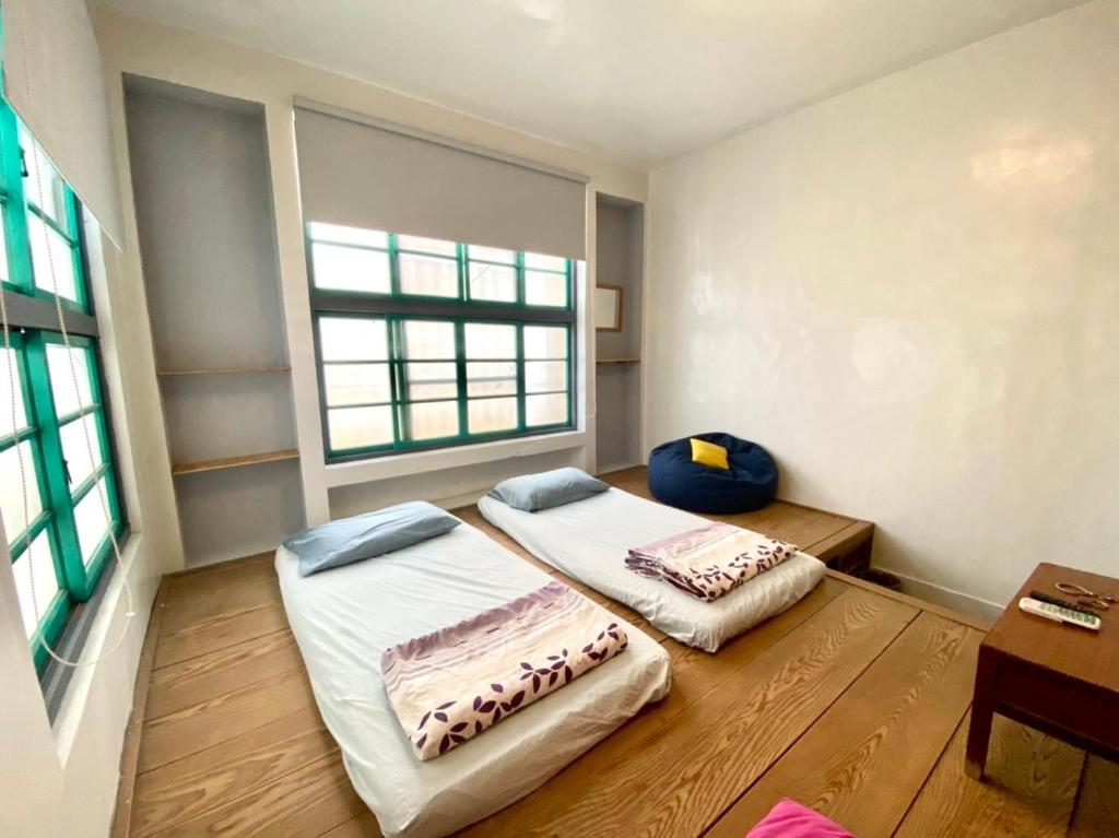 Cette chambre comprend 2 lits, une table et une fenêtre. dans l'établissement 樓仔厝, à Île Lamay