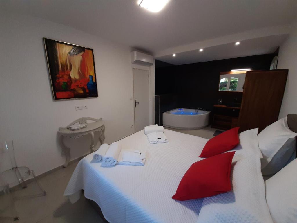 1 dormitorio con 1 cama con almohadas rojas y baño en VILLA RASOA chambre LOVE, en Cap d'Agde