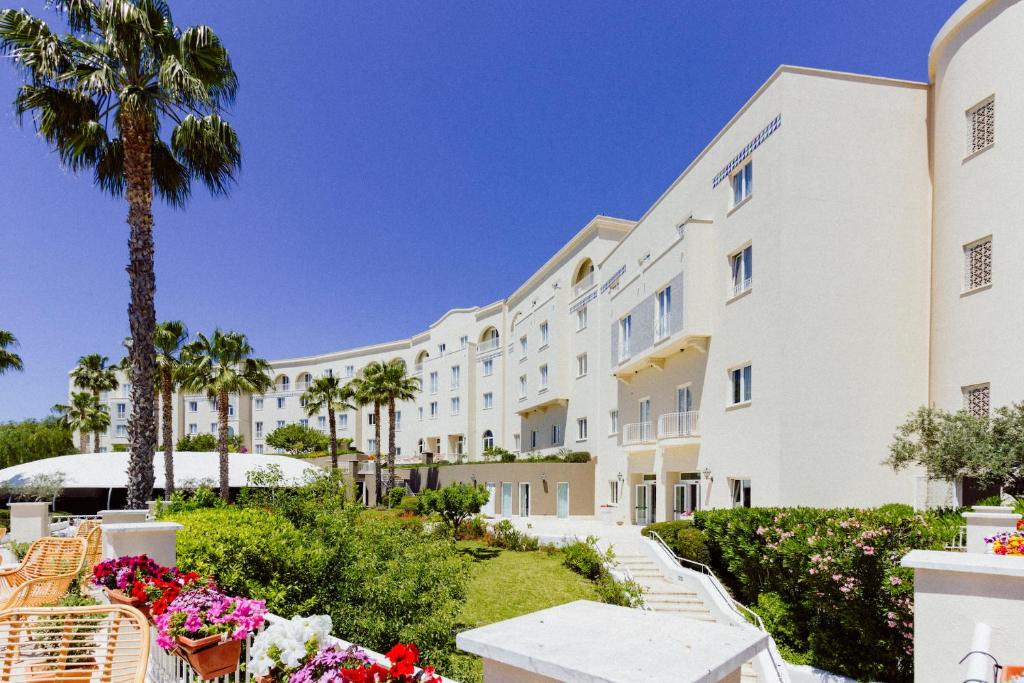 馬里內拉迪塞利的住宿－Mangia's Selinunte Resort，一排种有棕榈树和鲜花的白色建筑