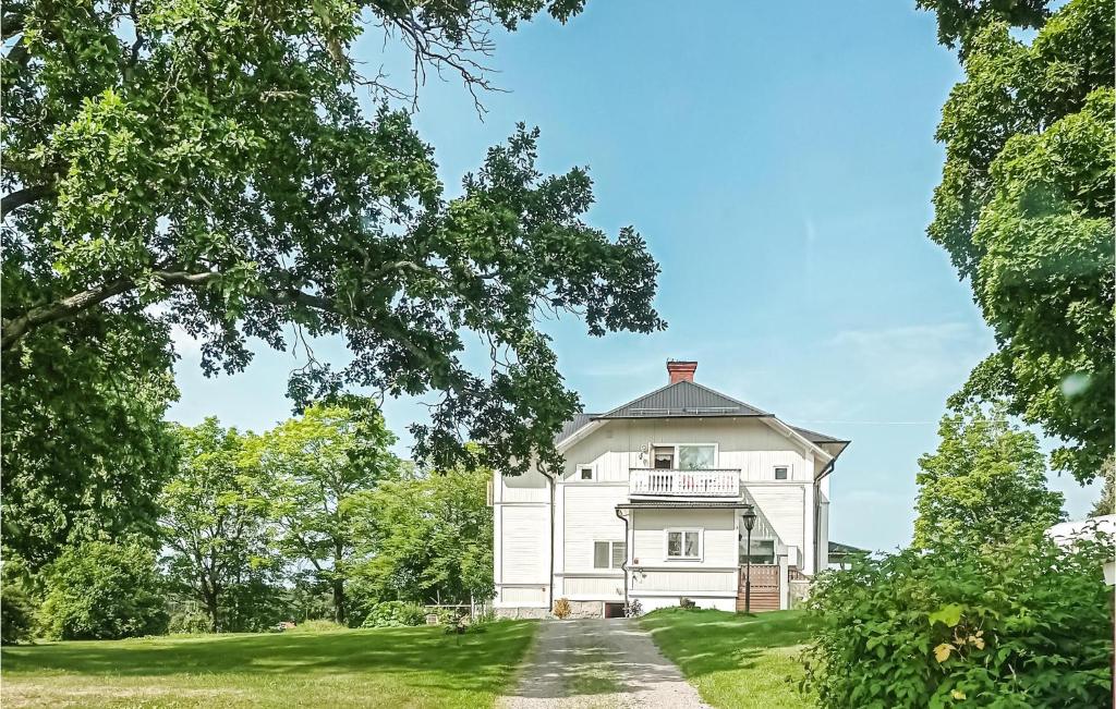 an old white house on a hill with trees at Awesome Apartment In Torsker With Wifi And 3 Bedrooms in Stjärnsund