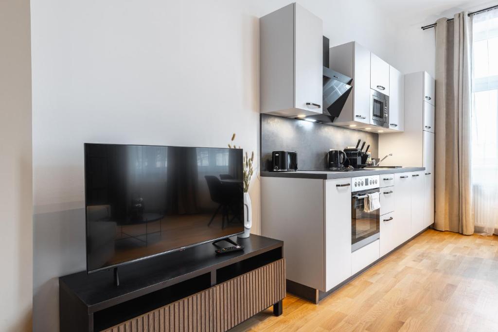 a kitchen with white cabinets and a black counter top at Trendy apt with - smart TV, coffee machine in Meidling in Vienna