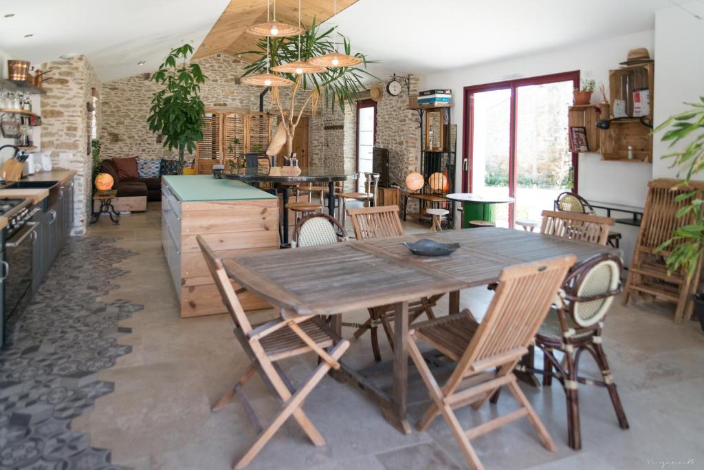 a dining room with a wooden table and chairs at Longère pierres&#47;modernité proche mer&#47;la guittière in Talmont