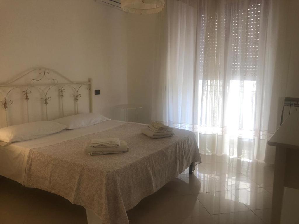 ein weißes Schlafzimmer mit einem Bett mit zwei Handtüchern darauf in der Unterkunft Il Cuore di Napoli in Neapel