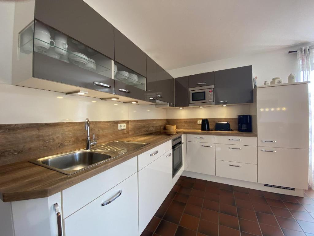 a kitchen with white cabinets and a stainless steel sink at Doppelhaushälfte Strandhus in Süderhöft