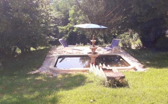 einen Pool mit einem Sonnenschirm und Stühlen sowie einem Brunnen in der Unterkunft Manoir Demouret Sarlat in Sarlat-la-Canéda