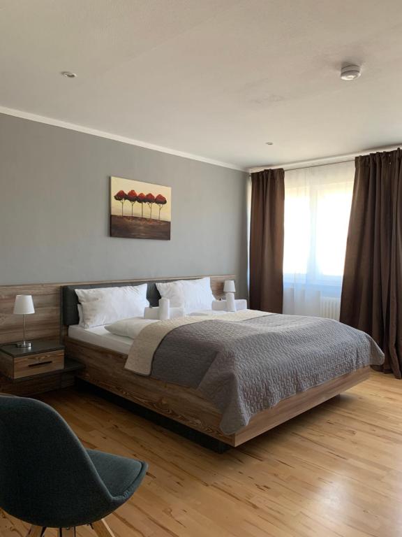a bedroom with a large bed and a chair at HGH - Hotel Garni Helbig in Neustadt an der Weinstraße