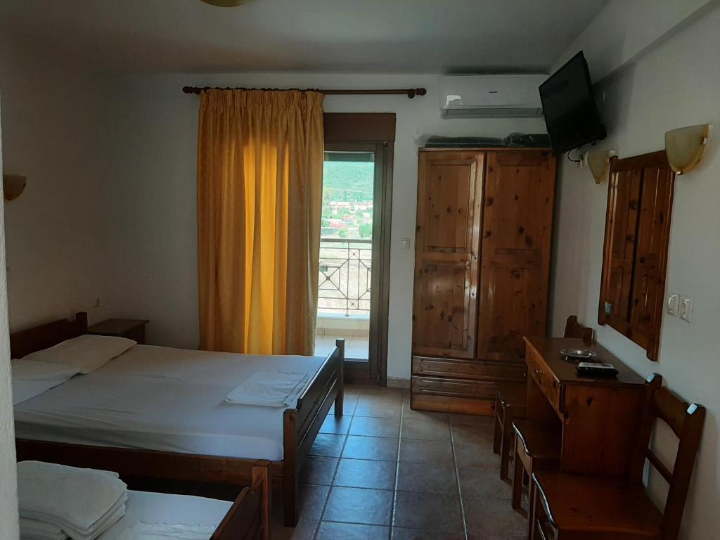 a bedroom with two beds and a large window at Hotel Kosmas in Sarti