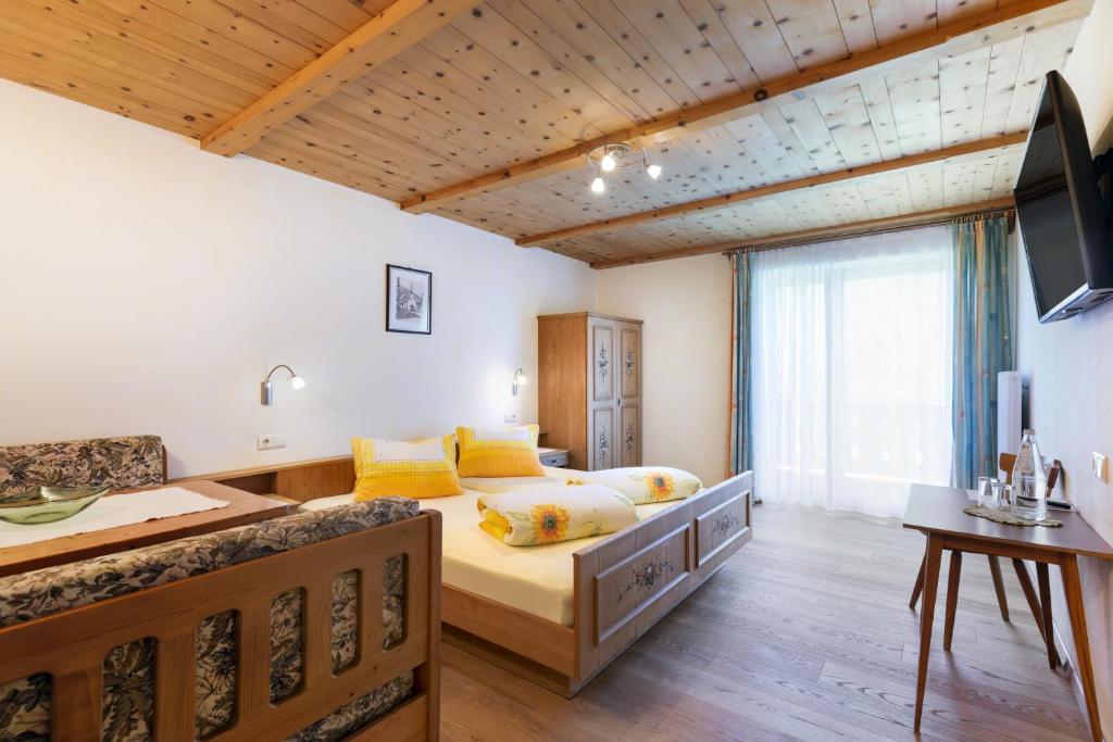 a bedroom with a bed and a desk and a television at Hotel Chavalatsch in Tubre