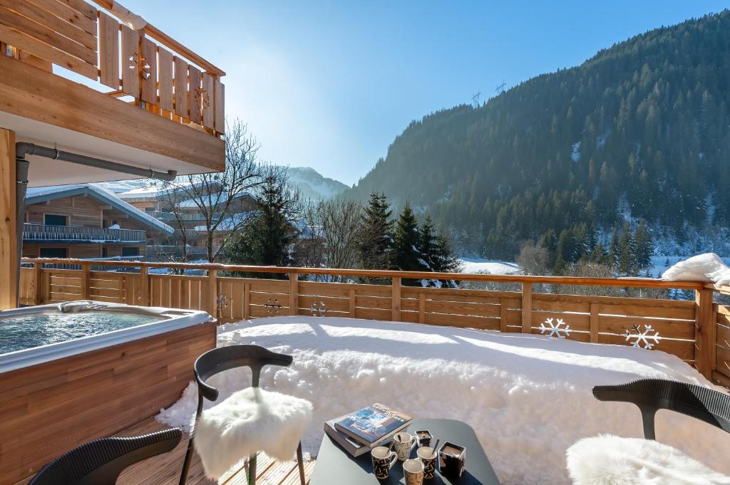 a hot tub on a deck with snow on the ground at Quintessence - Apt B303 - BO Immobilier in Châtel