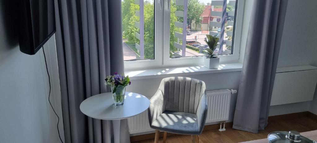una ventana con una mesa y una silla y un jarrón de flores en Pepleri Studio 68 en Tartu