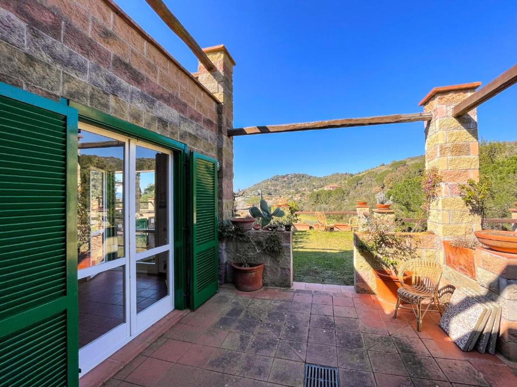 a patio with green doors and a view of the mountains at Il Giardino del Volterraio in Rio nellʼElba