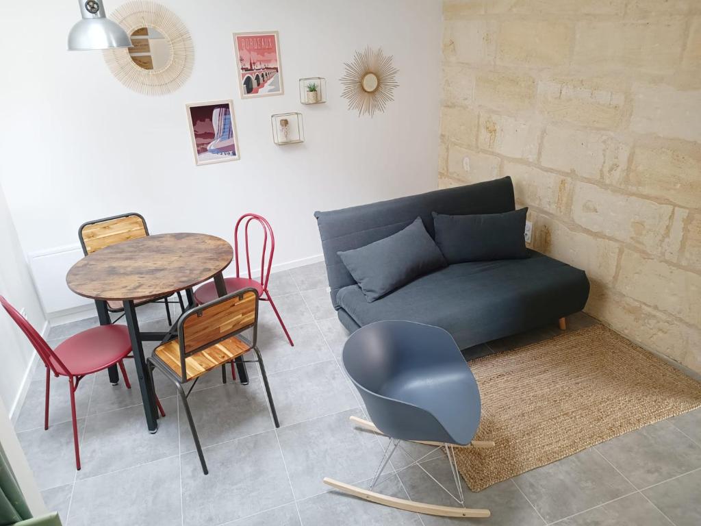 Immeuble Centre Ville في Saint-Médard-de-Guizières: غرفة معيشة مع أريكة وطاولة وكراسي