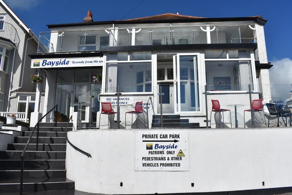 a house with chairs and a sign in front of it at Bayside Holiday Suits in Paignton