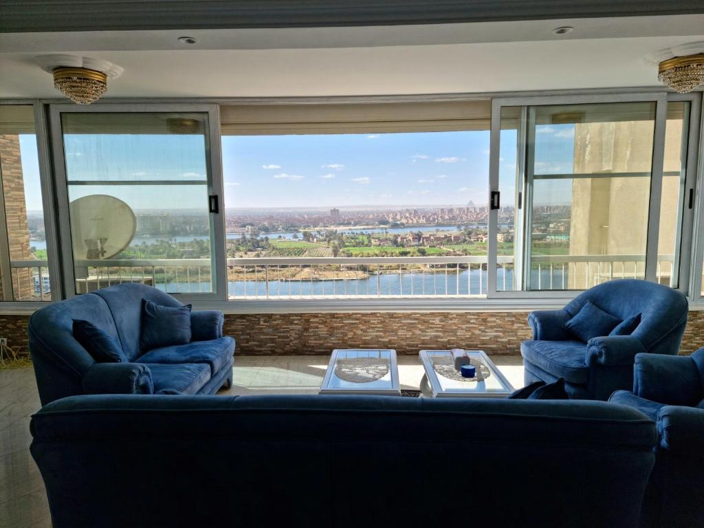 un soggiorno con 2 sedie blu e un tavolo di Amazing Nile View and Pyramids Apartment a Il Cairo