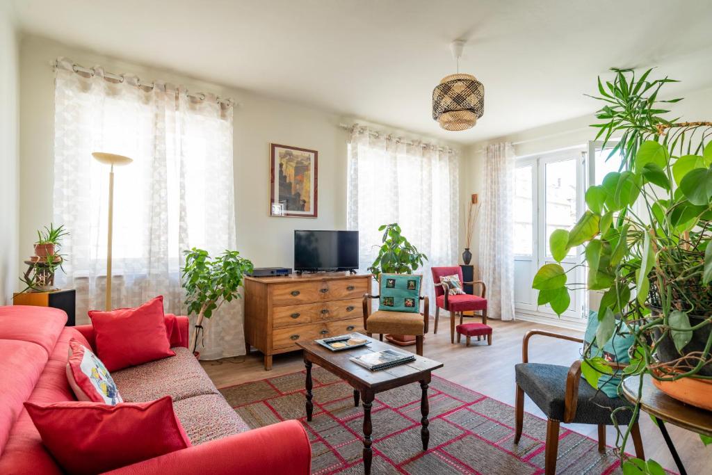 - un salon avec un canapé rouge et de nombreuses plantes dans l'établissement Strasbourg centre - quartier Gare & Petite France 
